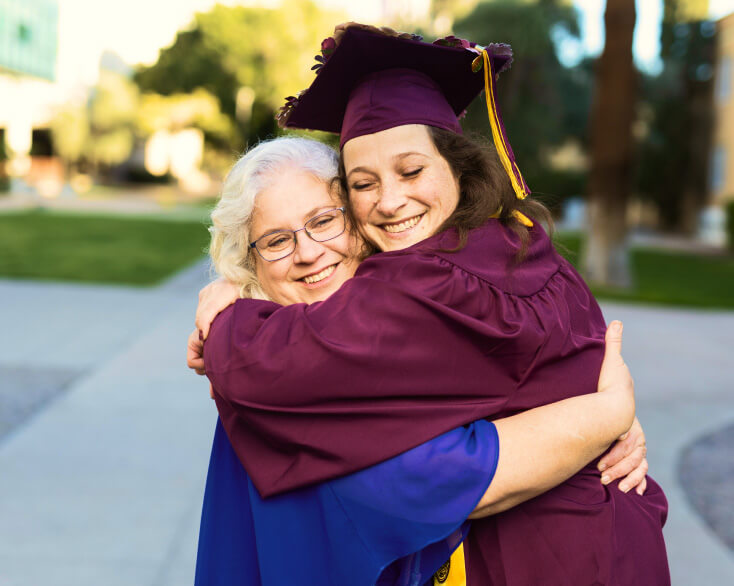 An ASU在线 graduate dressed in a cap and gown hugs her mom.